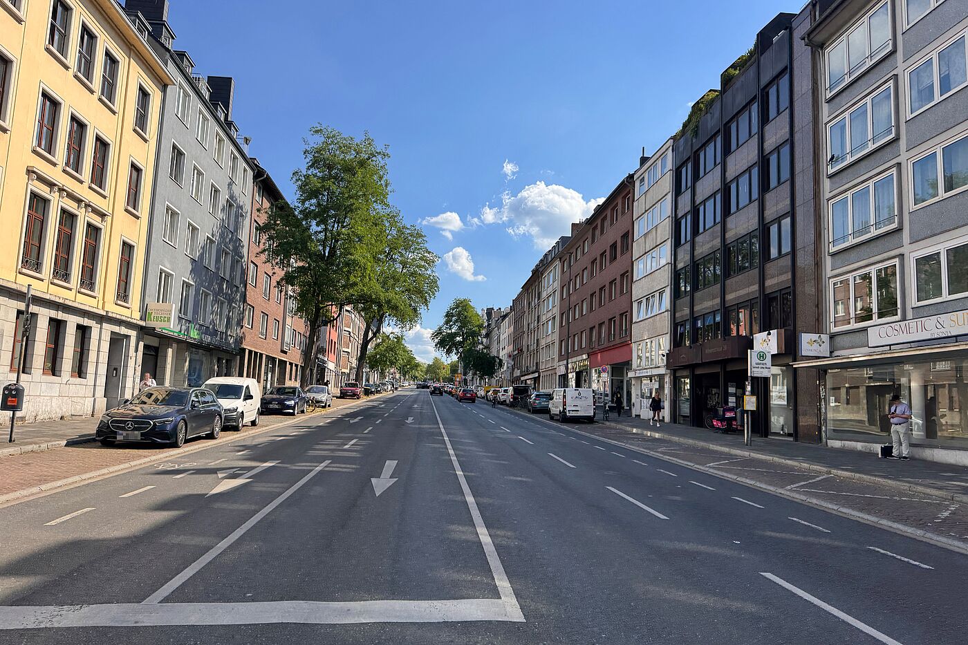 Geradeausblick entlang der Wilhelmstraße in Aachen. Die Straße hat mehrere Kfz-Spuren, parkende Fahrzeuge am Rand, hohe Häuserzeilen und nur wenig sichtbaren Raum für den Radverkehr.