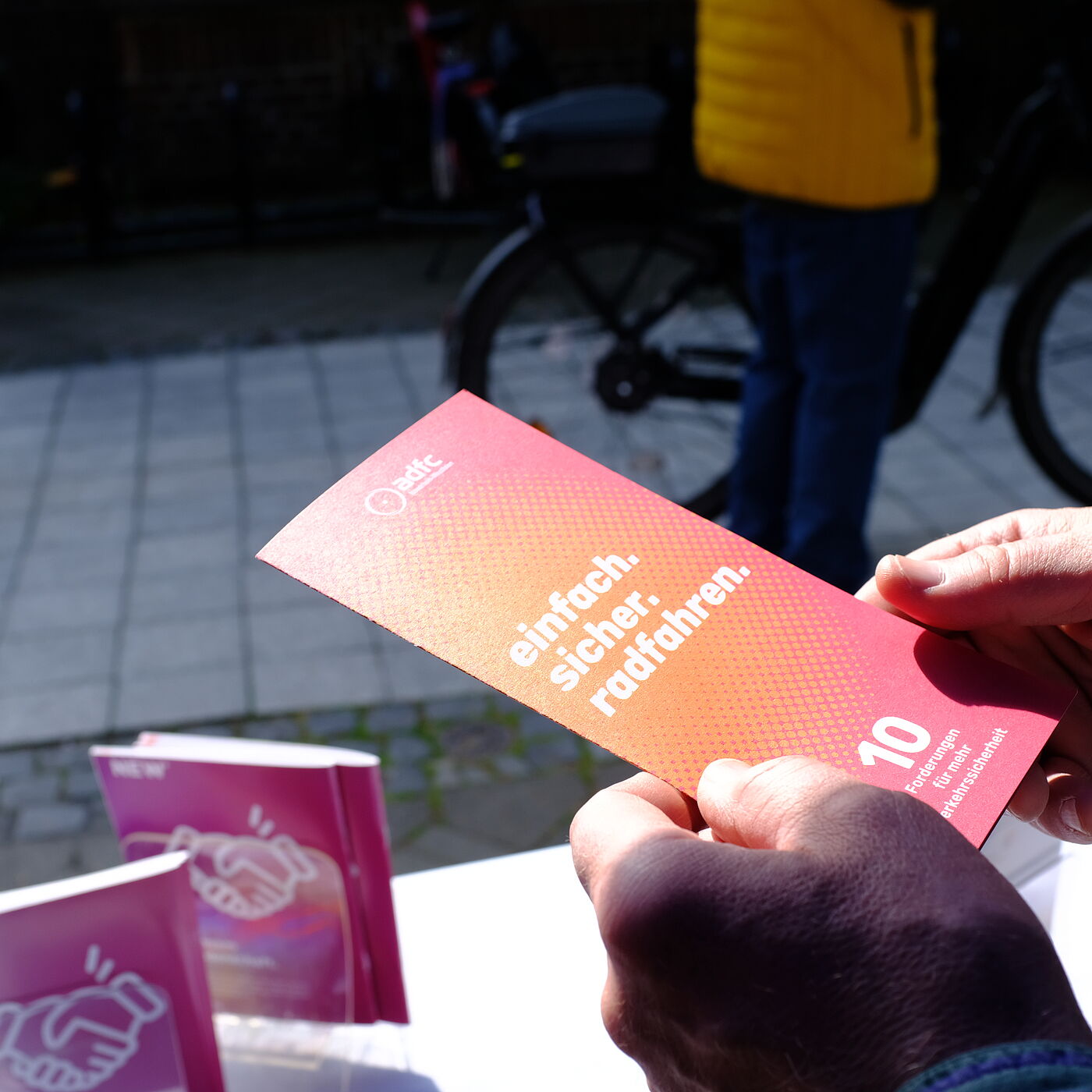 2026-04-17_Dormagen_Verkehrssicherheit__ADFC_NRW Eine Person hält einen Flyer.