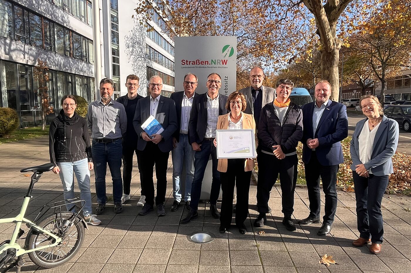 Am 7. November 2025 erhielt der Landesbetrieb Straßenbau Nordrhein-Westfalen (Straßen.NRW) am Betriebssitz Gelsenkirchen das Zertifikat "Fahrradfreundlicher Arbeitgeber" in Gold. Bei der Übergabe anwesend waren (v.l.) Maja Tölke (ADFC Gelsenkirchen), André Friedrich (Leiter Sachgebiet Radverkehr), Timon von Wiecken (Sachgebiet Radverkehr und Radverkehrskoordintor), Marc Zietan (ADFC NRW), Karsten van Dreuten (Leiter Abteilung Verwaltung und Service), Christoph Jansen (Leiter der Region II, designierter Nachfolger von Frau Dr. Beckefeld), Dr. Petra Beckefeld (Direktorin des technischen Bereichs und Sprecherin des Direktoriums), Christian Jung (Leiter Sachgebiet Immobilienstrategie/ bauaufsichtliche Angelegenheiten/TGA/ZD), Andreas K. Bittner (ADFC Projekt "Fahrradfreundlicher Arbeitgeber"), Dr. Sascha Kaiser (Direktor des kaufmännisch-juristischen Bereichs), Daniela Schnickmann (Sachgebiet Radverkehr).