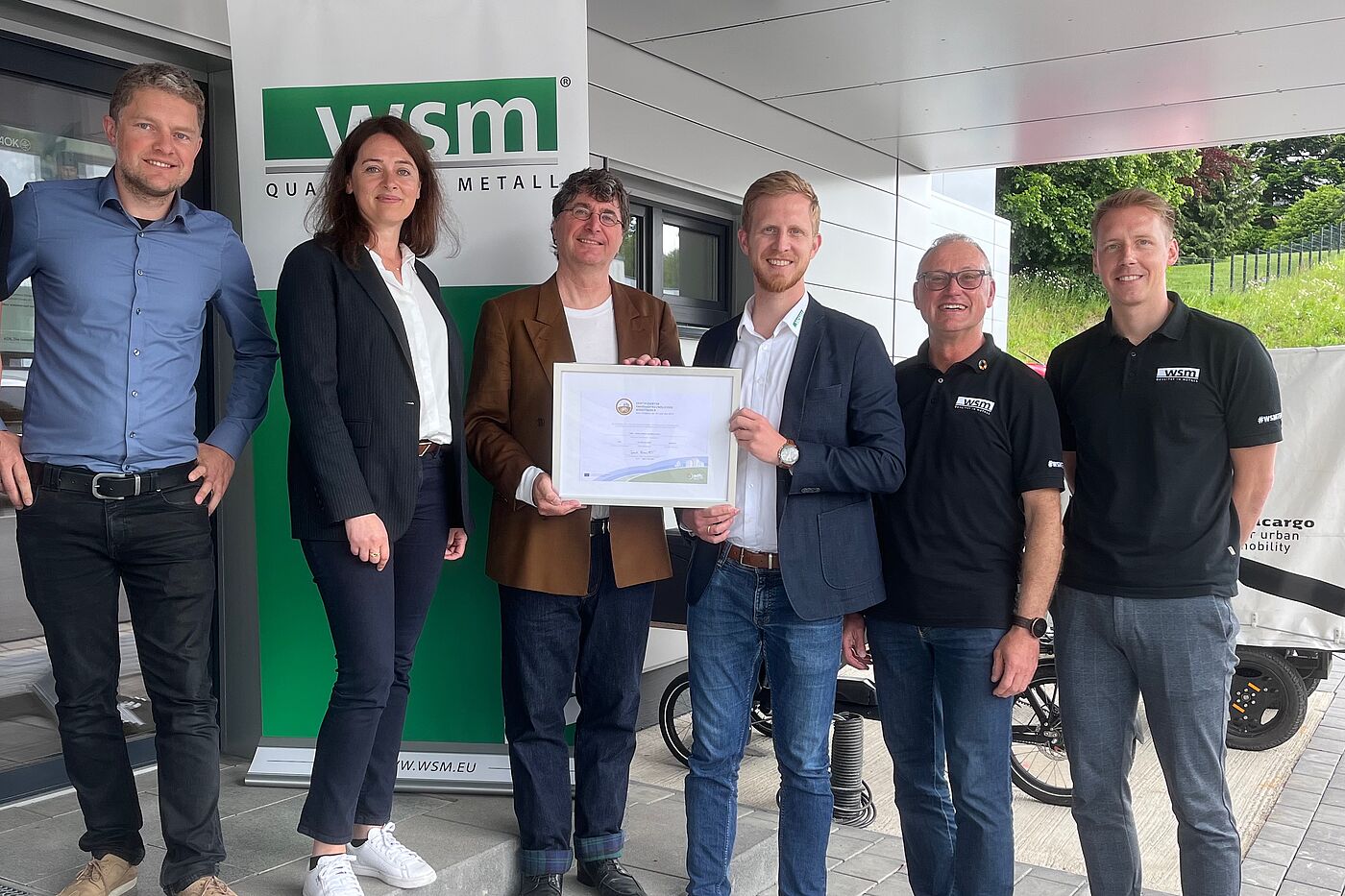Zertifikatsübergabe (Gold) an WSM – Walter Solbach Metallbau GmbH, Waldbröl am 22. Mai 2024 v.l. Rudolf Bergen (Mobilitäts- und Klimaschutz-Manager Stadt Waldbröl), Larissa Weber (Bürgermeisterin Stadt Waldbröl), Andreas K. Bittner (ADFC / "Fahrradfreundlicher Arbeitgeber"), Christoph Solbach (Geschäftsführer WSM), Andreas Hombach (Betrieblicher Mobilitätsmanager, IHK, WSM) und Rico Henseleit (Radverkehrskoordinator, WSM).