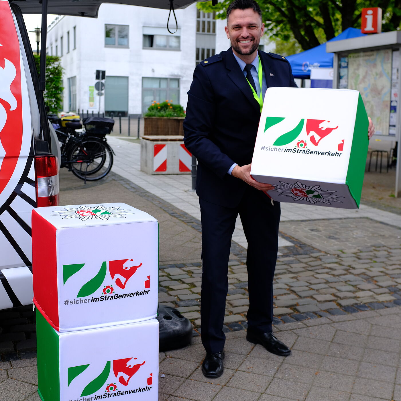 2026-04-17_Dormagen_Verkehrssicherheit__ADFC_NRW Die Polizei NRW packt die Verkehrssicherheit im Rahmen der Initiative #sicherimStraßenverkehr an. Ein Polizist hebt einen Kampagnenstein hoch.