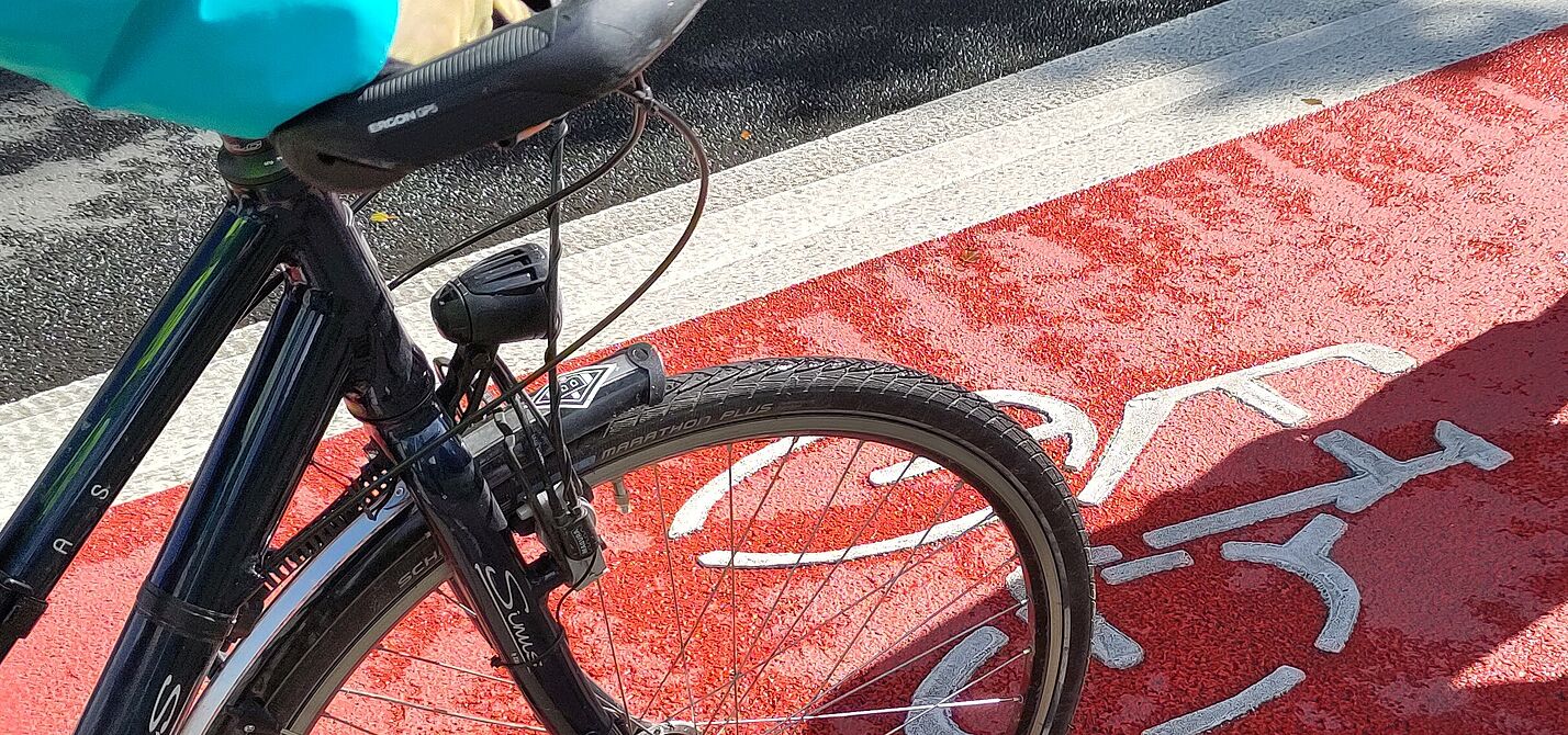 2023-08_LHA-Exkursion_MG_ADFC_NRW__23_.jpg Neu markierter Radfahrstreifen mit flächiger Roteinfärbung. Man sieht auch einen Fahrradlenker.