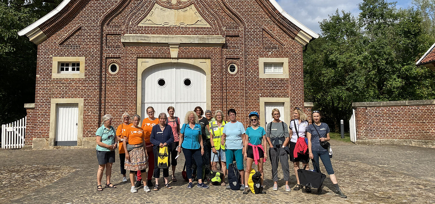 Radfahrerinnen in bunter Kleidung vor dem historischen Gebäude Haus Rüschhaus