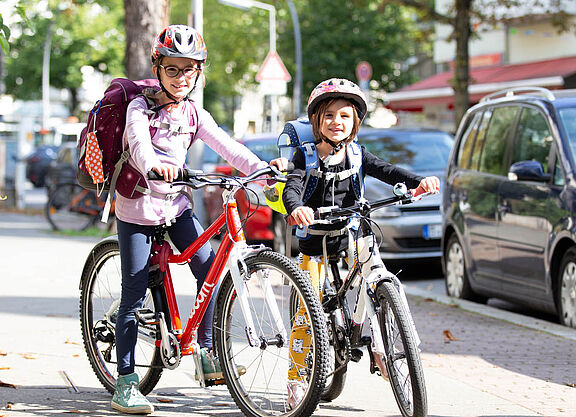 Mädchen mit Ranzen auf dem Fahrrad.