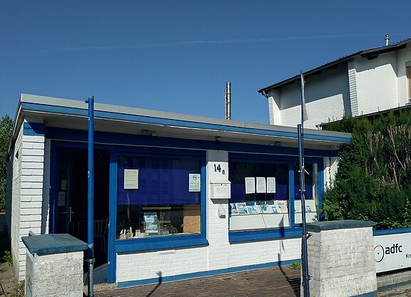 Ein weißer, gemauerter Bungalow mit blauen Tür- und Fensterrahmen.