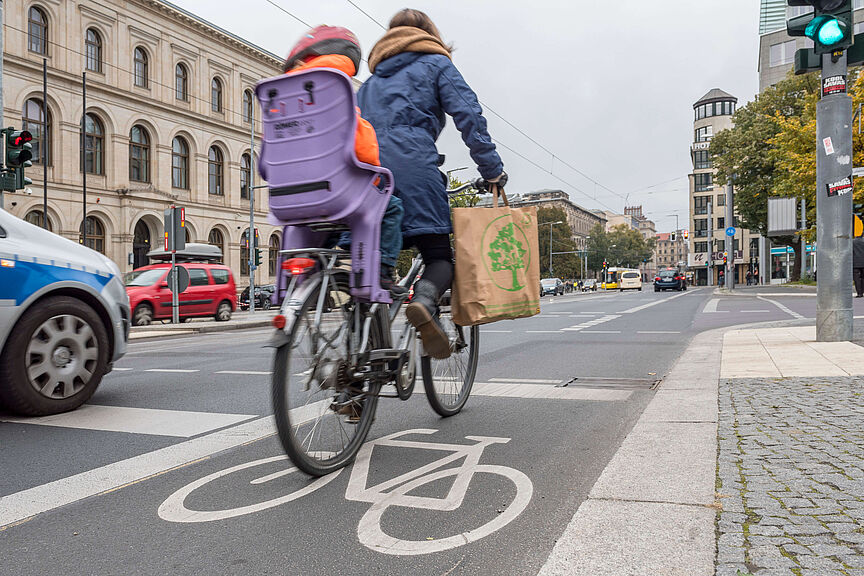 Fahrradfahren in der Stadt Frau mit Kind auf dem Rad in der Stadt unterwegs
