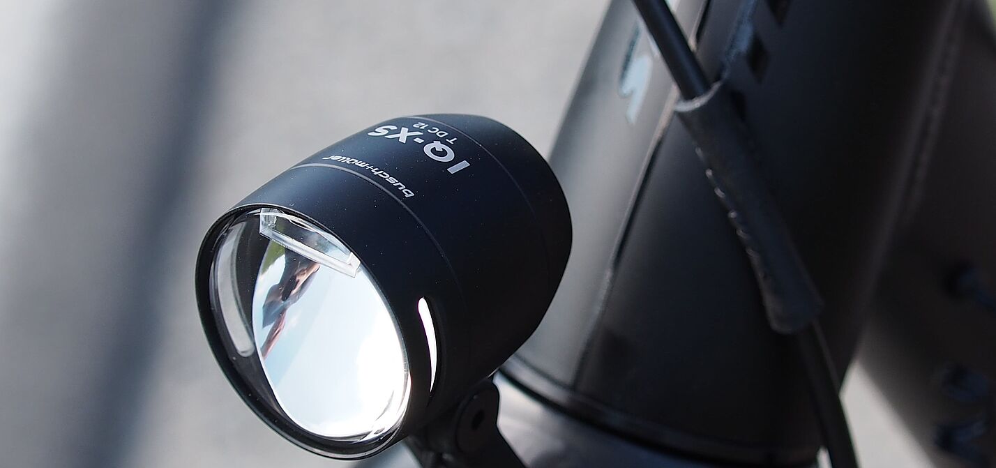 LED-Fahrradscheinwerfer Schwarzer LED-Fahrradscheinwerfer am silbernen Fahrradlenker montiert.